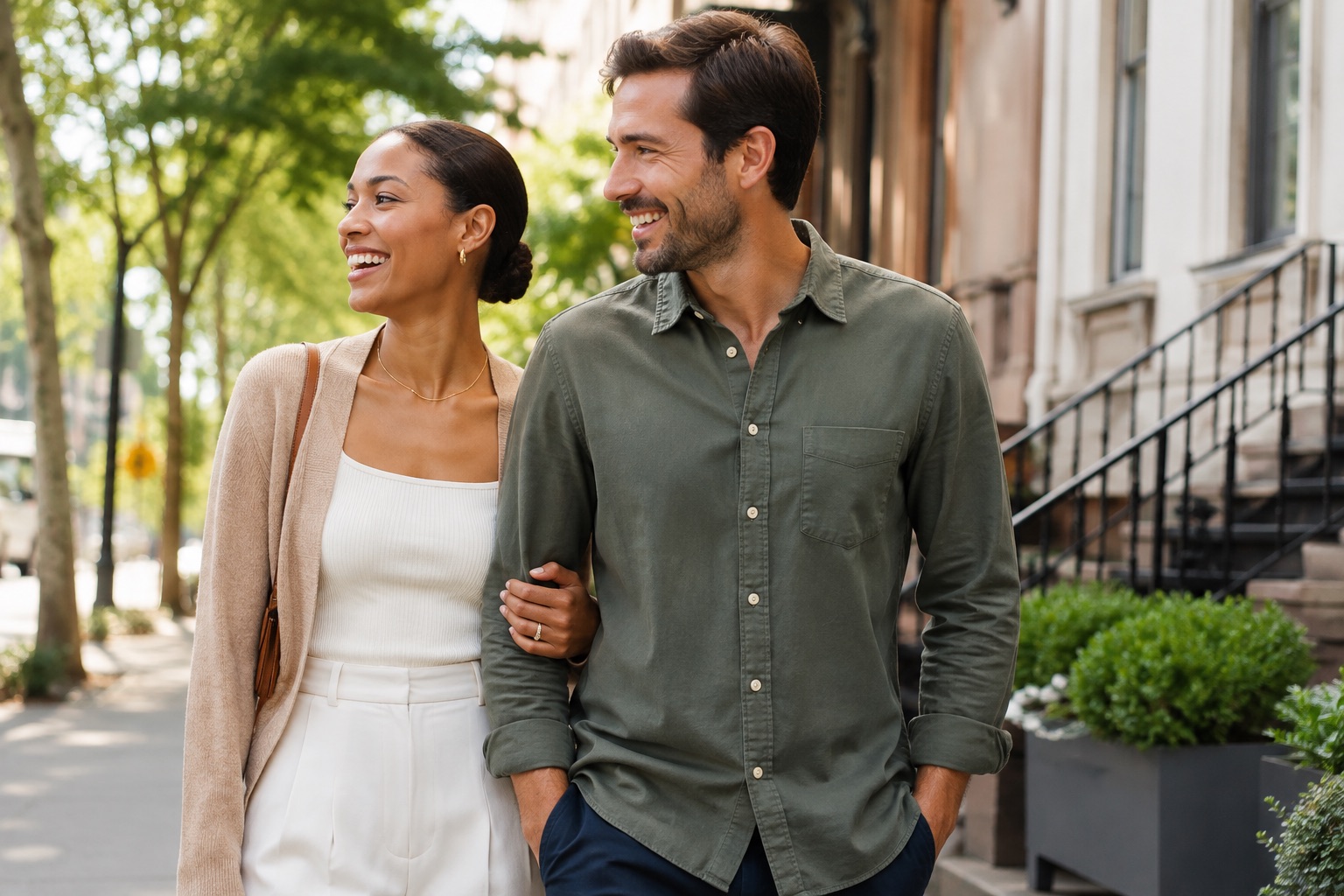 A couple in their thirties walking and talking on a city street in the evening.